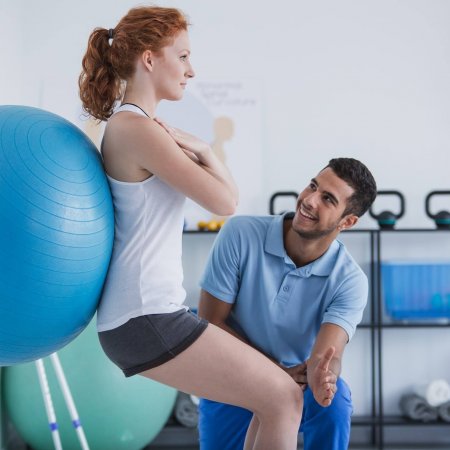 Smiling professional personal trainer helping sportswoman exerci